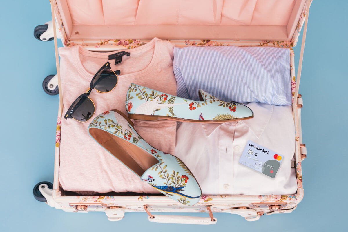 En packad resväska med solglasögon, kläder och Lån & Spar Bank Mastercard. 