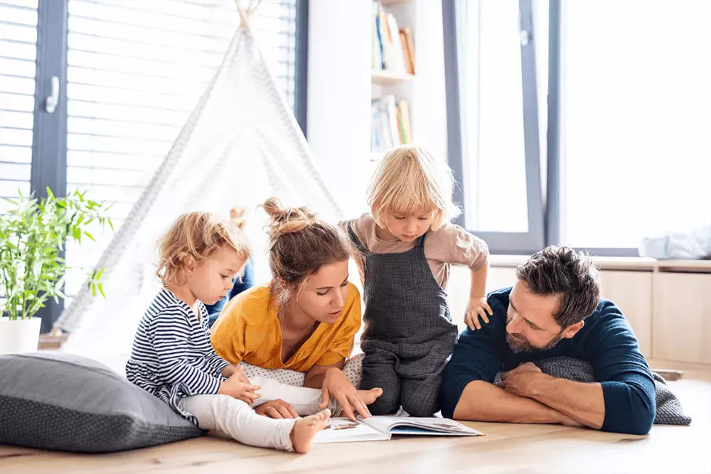 Två föräldrar och två barn sitter i ett barntält inomhus