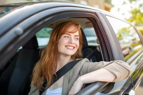 En kvinna sitter i bilen en härlig dag